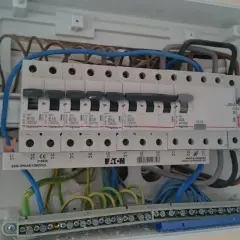 Wnętrze rozdzielnicy elektrycznej z widocznym zabezpieczeniem przedlicznikowym, wyłącznikami i przewodami.