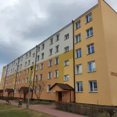 Długi blok mieszkalny przy ul. Łukaszyńskiej 15, pomalowany na żółto i biało. Spółdzielnia mieszkaniowa nie chce naprawić dachu, mimo że przecieka.
