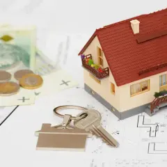Model domu, klucze, pieniądze i plany architektoniczne. To wszystko składa się na kosztorys inwestorski.