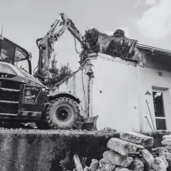 Koparka niszczy budynek. Pamiętaj, ile jest ważne pozwolenie na rozbiórkę, by uniknąć problemów prawnych.