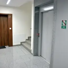 Korytarz z drzwiami nr 22 i windą. Warto pomyśleć o ubezpieczenie mieszkania a wymiana pionów, gdy planujesz remont.