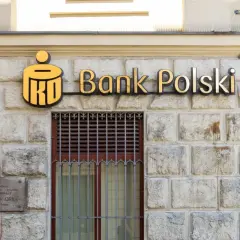 PKO Bank Polski oferuje pko kredyt hipoteczny bez wkładu własnego. Złote logo banku na kamiennej fasadzie.