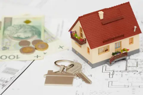 Model domu, klucze, pieniądze i plany architektoniczne. To wszystko składa się na kosztorys inwestorski.