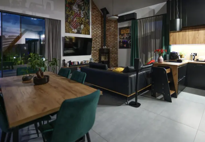 Nowoczesny salon z jadalnią i aneksem kuchennym. Stylowe wykończenie domu, gdzie koszty idą w parze z designem.