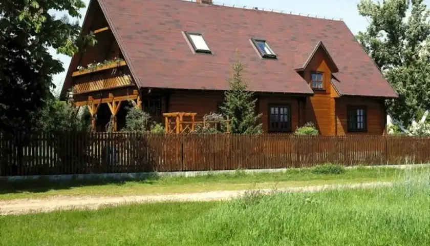 Drewniana zabudowa zagrodowa, idealna dla rolników, z werandą i drewnianym płotem.