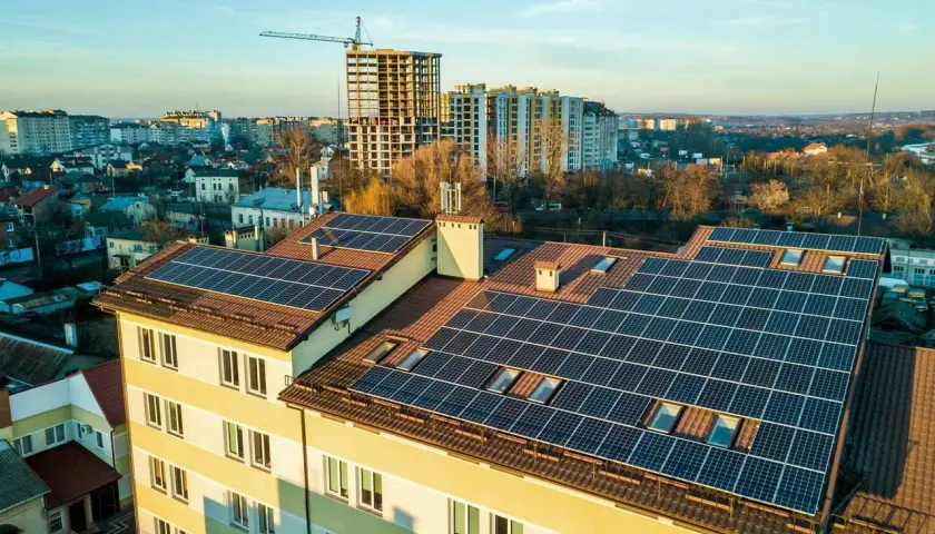 Panele fotowoltaiczne na dachu bloku mieszkalnego. Fotowoltaika we wspólnocie mieszkaniowej to przyszłość zielonej energii.