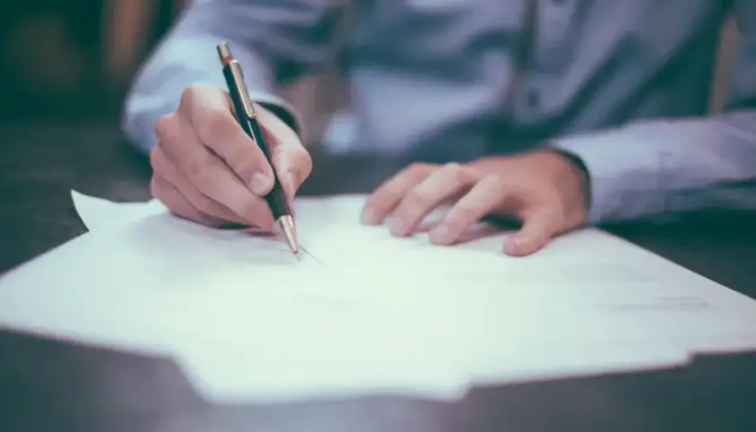 Mężczyzna pisze ręcznie dokument, który może być wzorem skargi na zarządcę nieruchomości.