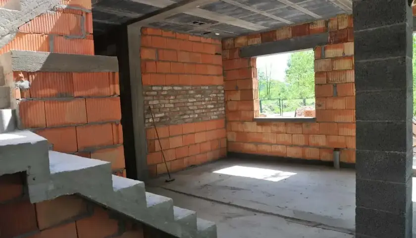 Budynek gospodarczy w trakcie budowy, z ceglanymi ścianami i betonowymi schodami. Czy w takim miejscu można mieszkać?