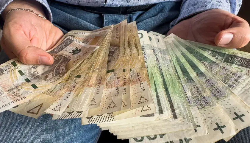 Ręce trzymające plik banknotów, gotowe na darowiznę dla dziecka.
