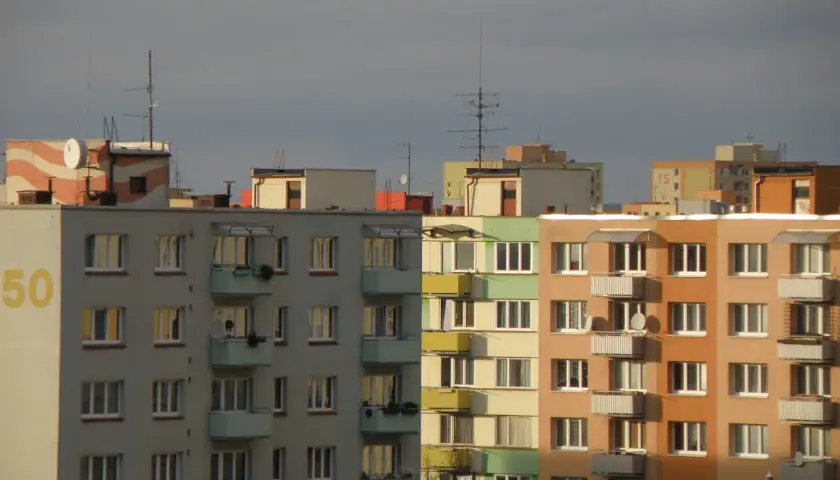 Bloki mieszkalne z balkonami, na dachu jeden z nich widnieje napis "50". W tle inne budynki, niebo zachmurzone. Warto pamiętać o fundusz remontowy przepisy.
