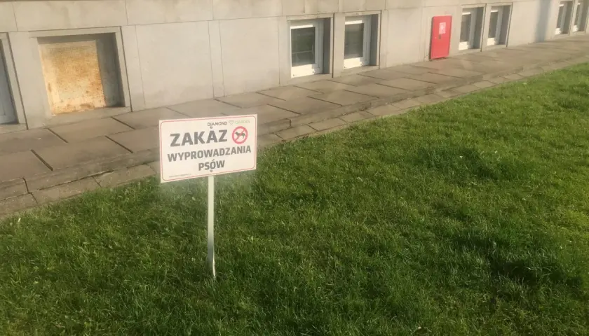 Tabliczka informuje o zakazie wyprowadzania psów na terenie wspólnoty.