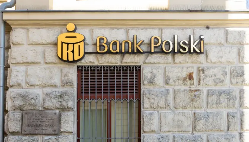 PKO Bank Polski oferuje pko kredyt hipoteczny bez wkładu własnego. Złote logo banku na kamiennej fasadzie.