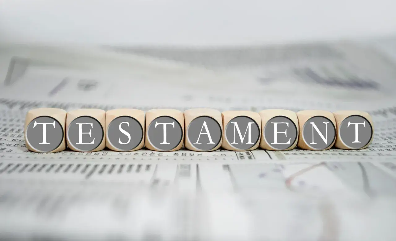 Drewniane klocki z literami tworzą słowo "TESTAMENT", symbolizując prawo dziedziczenia i testament.