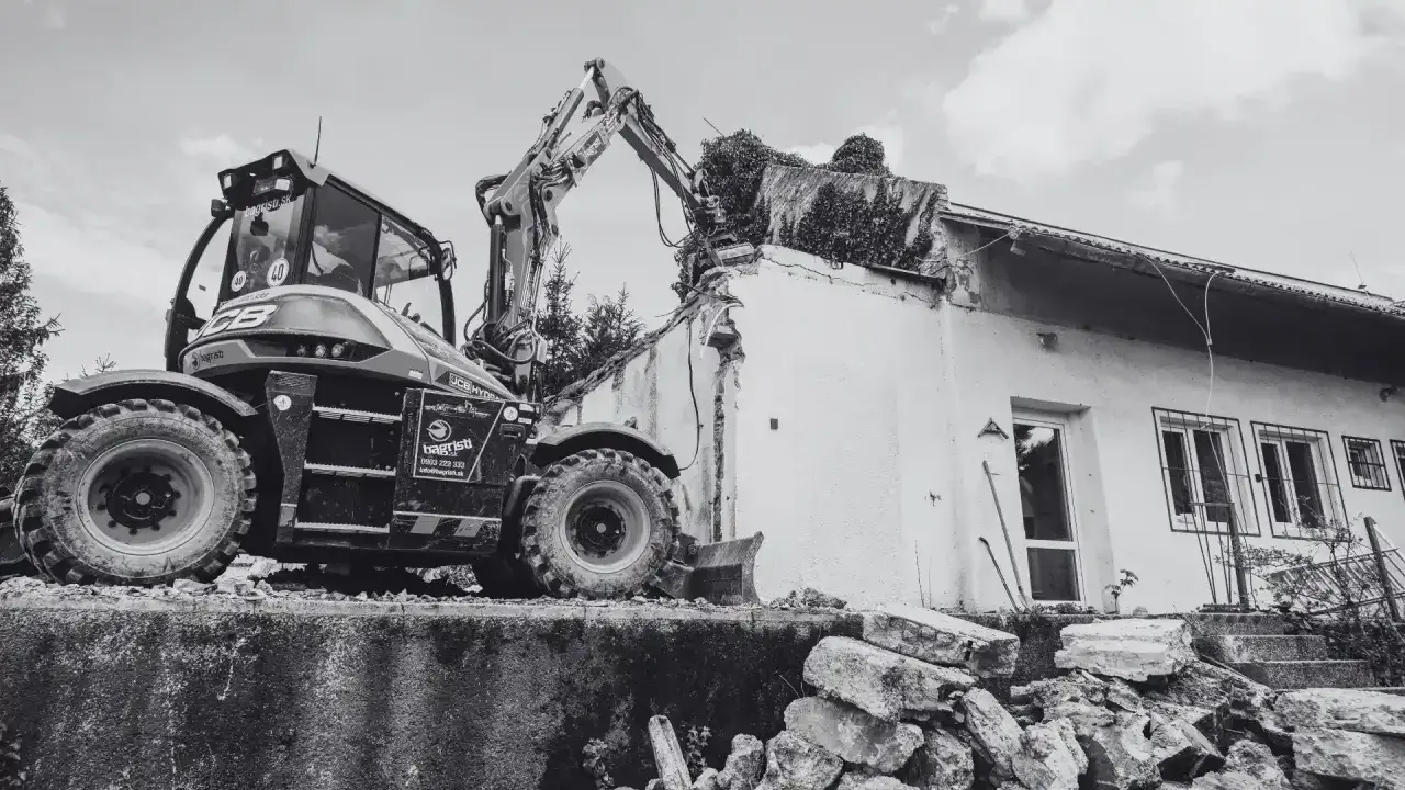 Koparka niszczy budynek. Pamiętaj, ile jest ważne pozwolenie na rozbiórkę, by uniknąć problemów prawnych.