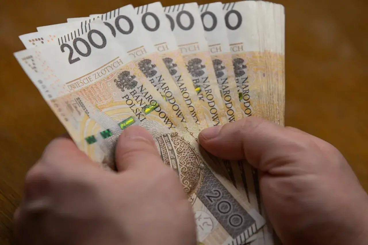 Dłonie trzymają stos banknotów po 200 zł. To hojna darowizna w pierwszej linii, która pomoże potrzebującym.